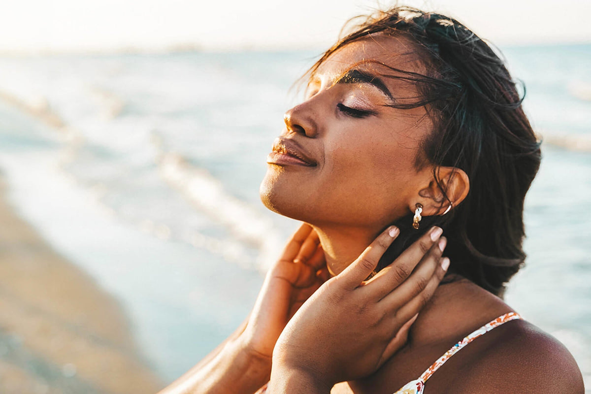 Woman with dark textured hair enjoying a sunny beach day near the shoreline
